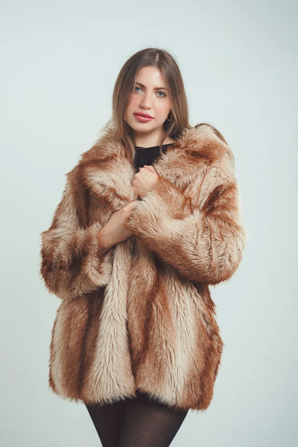 Studio fashion portrait of a model wrapped in a statement faux-fur coat