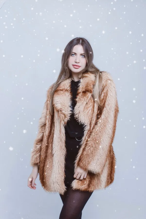 Fashion portrait in a fur coat with falling snow