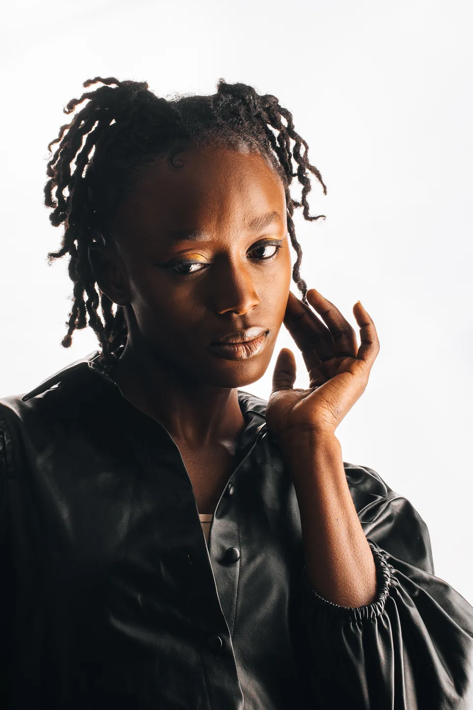 Sculptural fashion portrait in black leather against a luminous white background