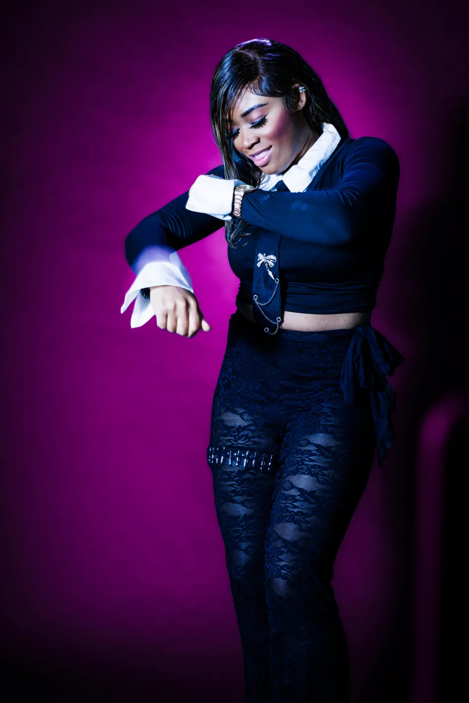 Vibrant fashion portrait of a model in black against a magenta studio background
