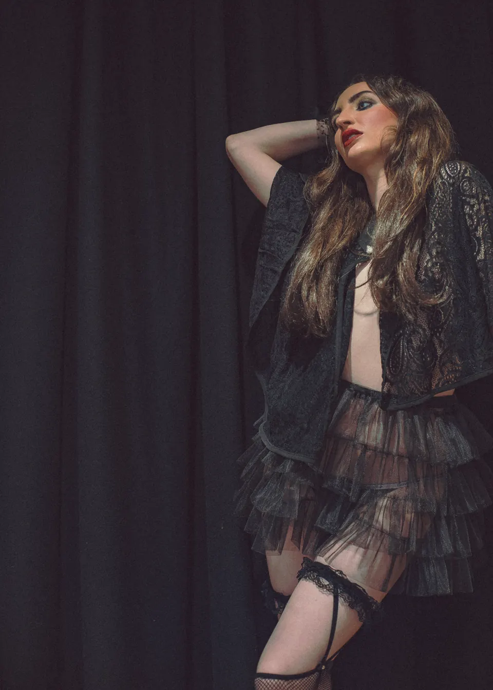 Woman styled in dramatic sheer black layers and a sculptural hat