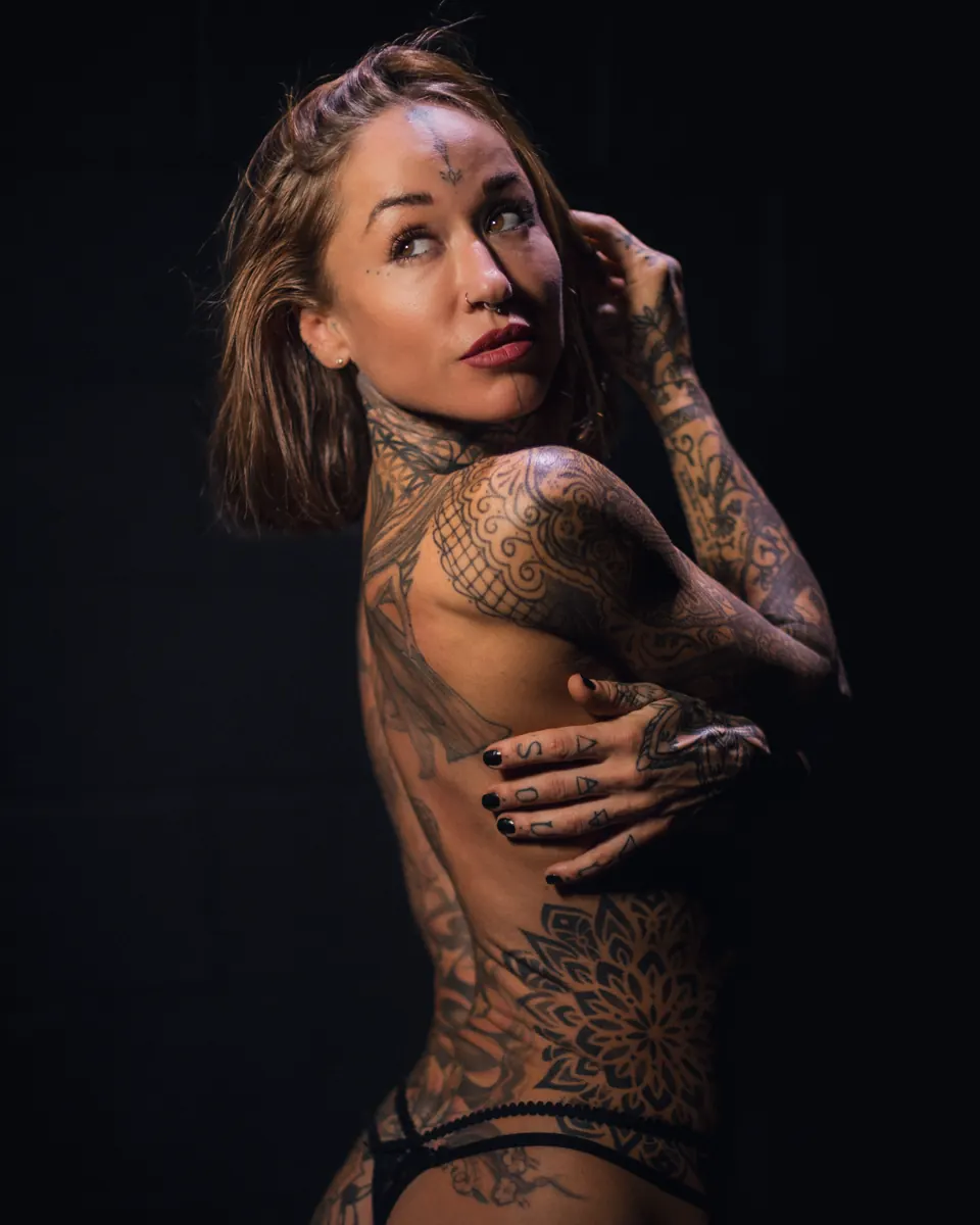 Tattooed woman in a softly lit black-background portrait