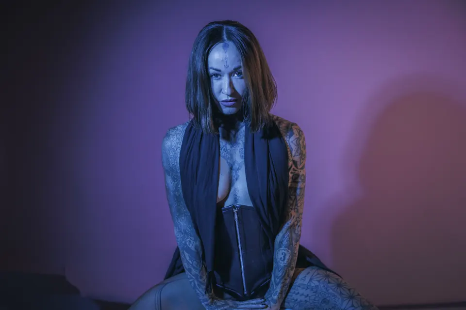 Tattooed woman in a blue and violet studio portrait